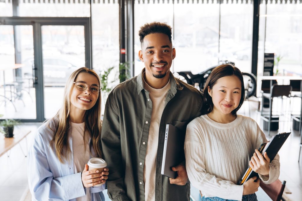 Diverse university students smiling and holding study materials in cafeteria