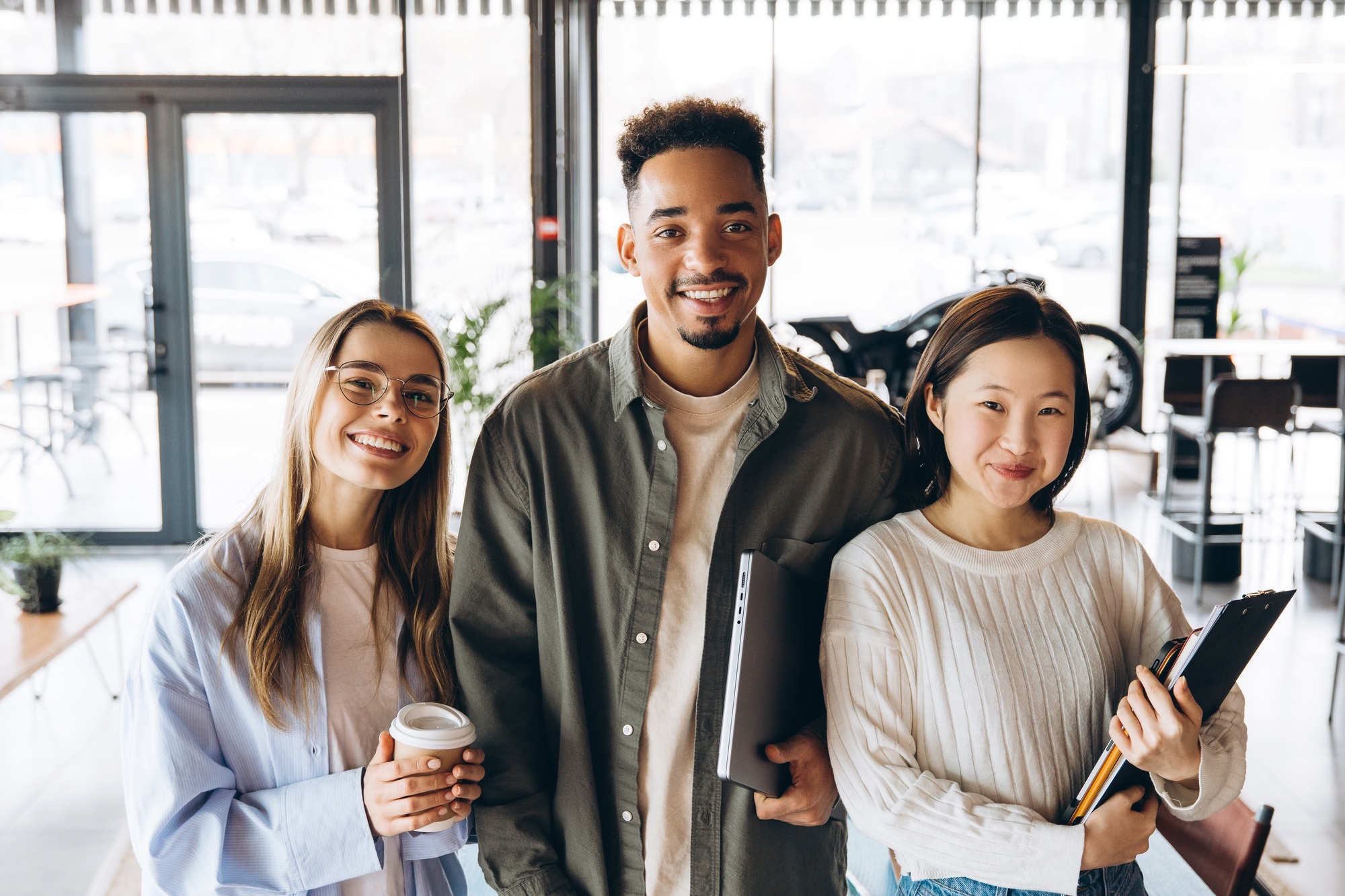 Diverse university students smiling and holding study materials in cafeteria